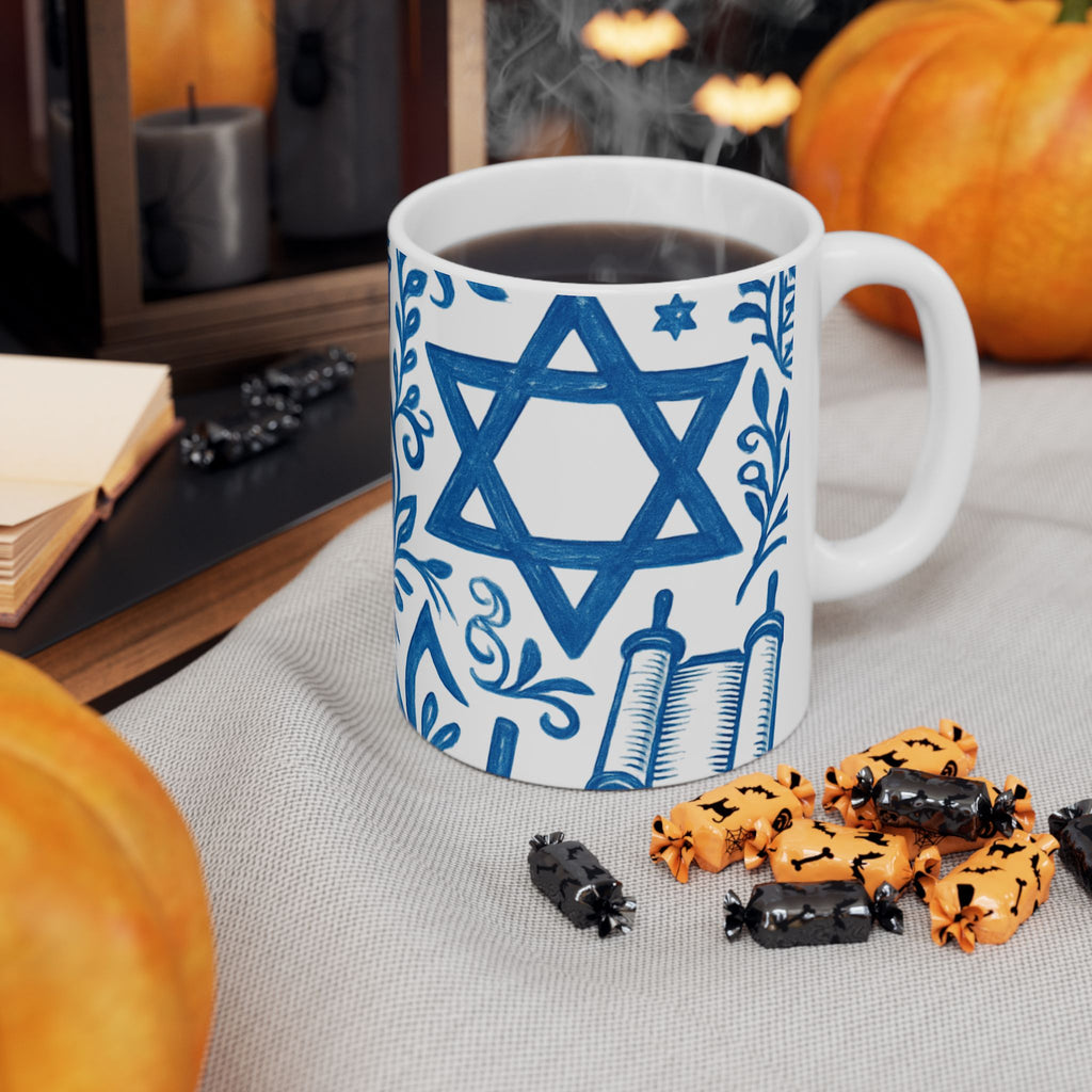 Mug with Star of David design on a table with Halloween-themed treats and pumpkins.