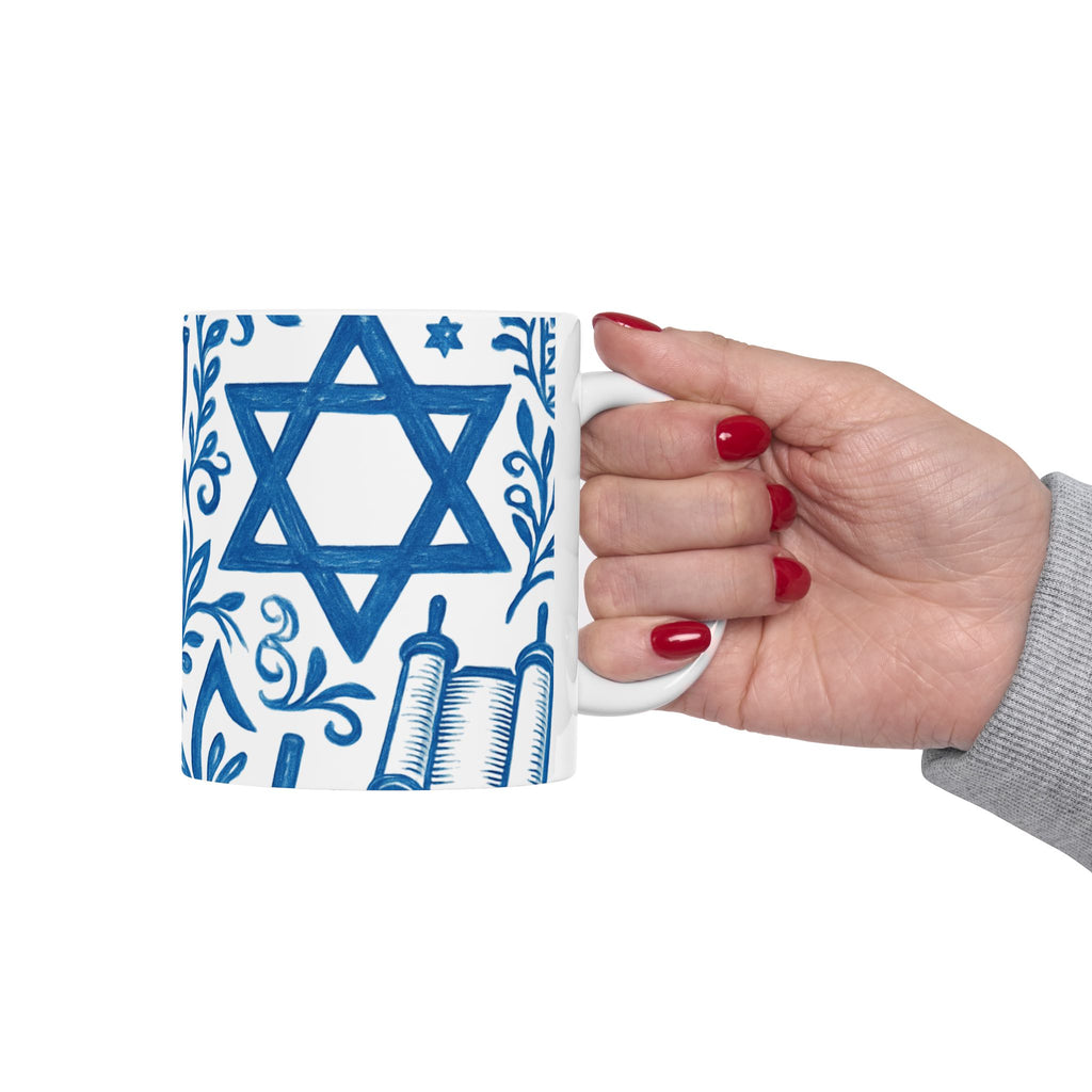 Hand holding a mug with Star of David and Torah design on a white background