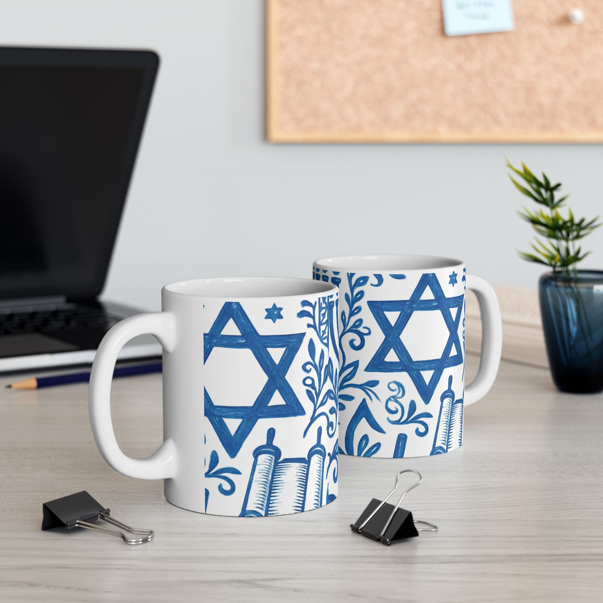 Two mugs with blue Star of David design on a desk with office items.