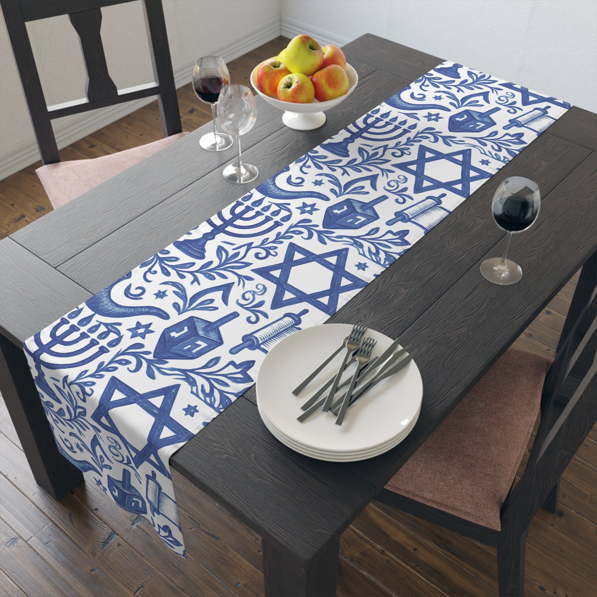 Dining table with a blue and white Hanukkah-themed table runner, plates, and wine glasses.